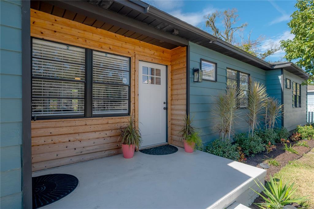 A front porch with a white door, wood siding, and blue horizontal lap siding — 4110 N MARGUERITE STREET, TAMPA, FL