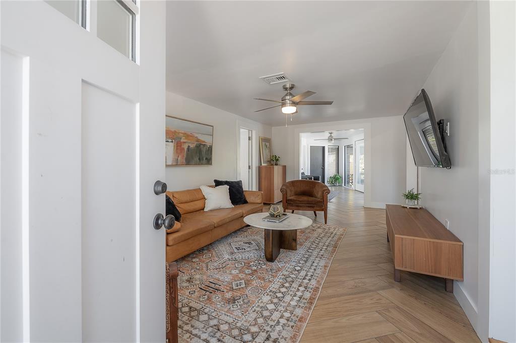 A living room features a leather sofa, patterned rug, wood-look tile flooring, and a television — 4110 N MARGUERITE STREET, TAMPA, FL