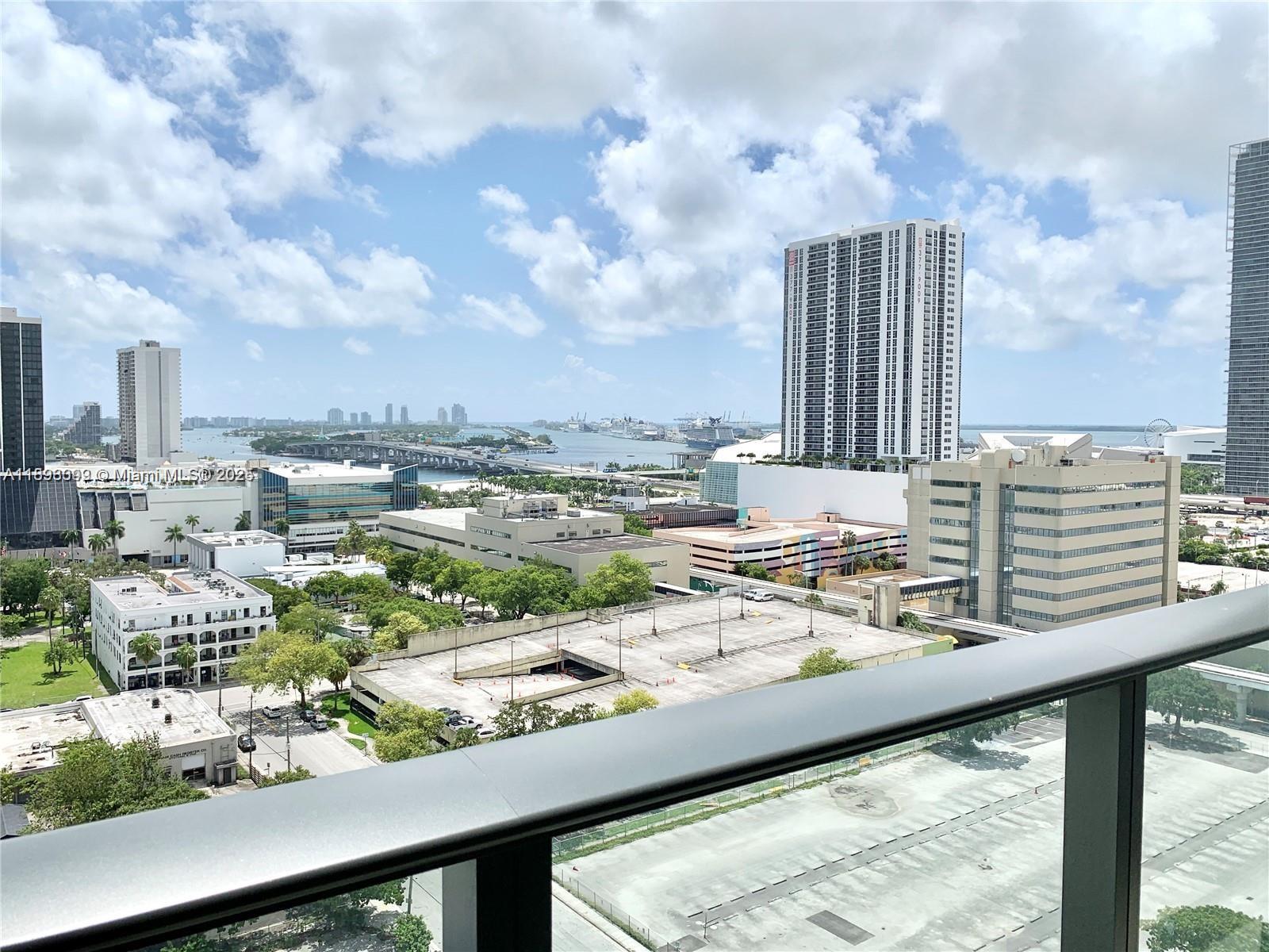 An elevated view from a balcony overlooks a city skyline, a bridge, and the ocean — 1600 NE 1st Ave # 1003, Miami FL 33132, MIAMI, FL