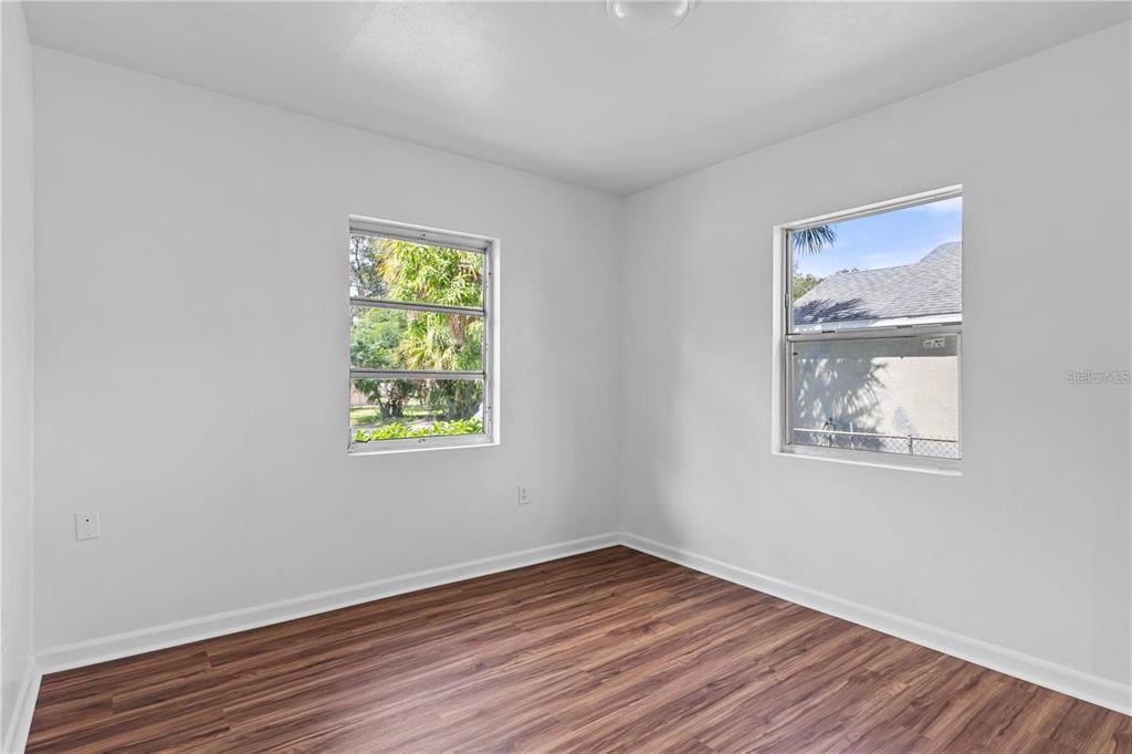 An empty bedroom features white walls, wood-look flooring, and two windows — 2314 N OSPREY AVENUE, SARASOTA, FL