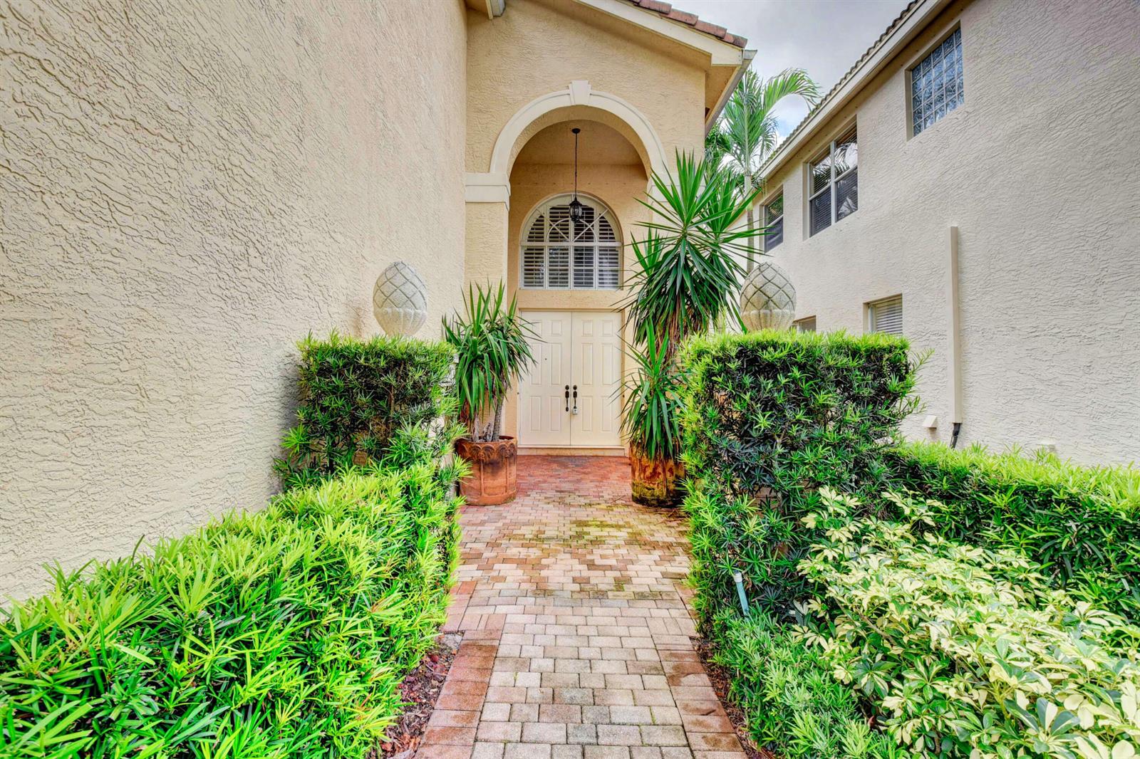 A brick walkway leads to the double front doors of a stucco house with landscaping — 8957 Sandy Crest Lane, Boynton Beach FL 33473, BOYNTON BEACH, FL