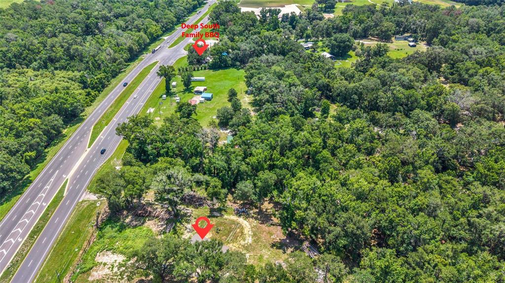 An aerial view shows a highway running alongside a wooded property with several small buildings — 24050 CORTEZ BOULEVARD, BROOKSVILLE, FL