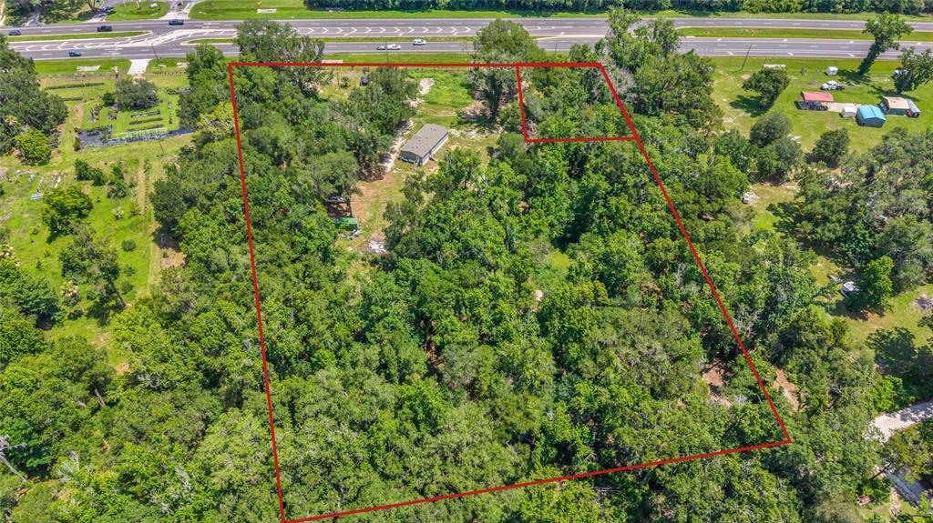 An aerial view shows a large, wooded plot of land outlined in red near a highway — 24050 CORTEZ BOULEVARD, BROOKSVILLE, FL