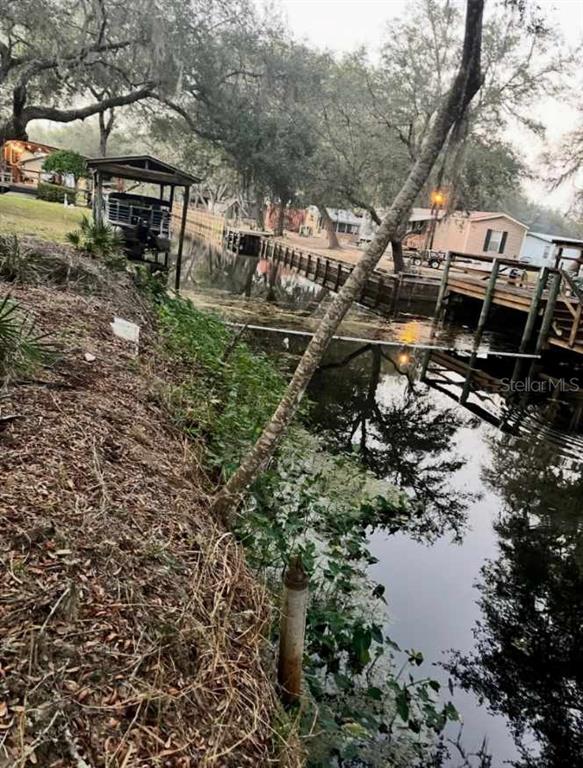 A view of a canal with a boat dock and wooden bulkhead along the shore — 18625 NE 238TH TERRACE, FORT MC COY, FL
