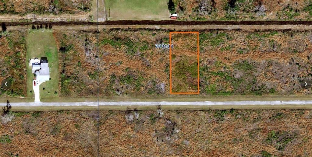 An aerial view shows a rectangular vacant lot outlined in orange amidst undeveloped land — 220 MAGNOLIA DRIVE, INDIAN LAKE ESTATES, FL