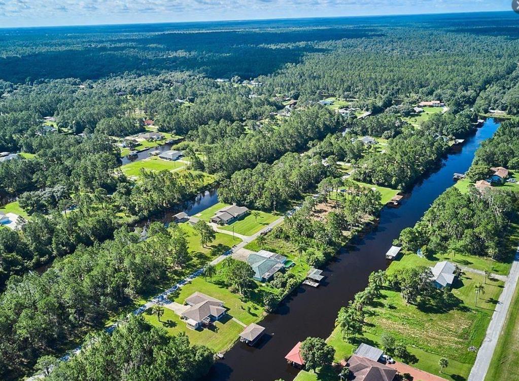 An aerial view shows houses along a canal surrounded by dense trees and green lawns — 220 MAGNOLIA DRIVE, INDIAN LAKE ESTATES, FL
