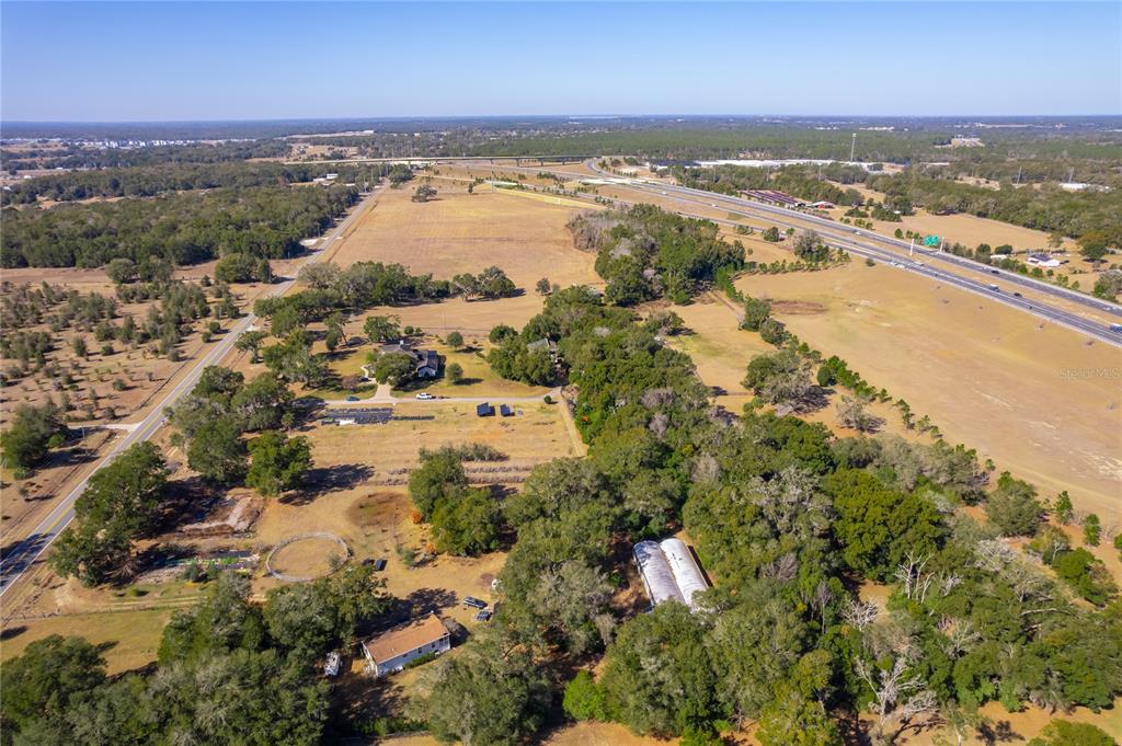 An aerial view shows a rural property with houses, outbuildings, and trees near a highway — 250 MCGUIRE RD, APOPKA, FL