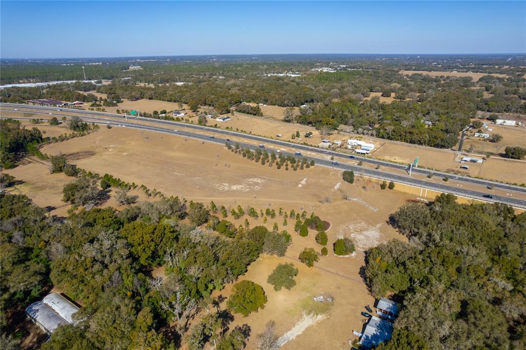 An aerial view shows a large, grassy lot adjacent to a multi-lane highway — 250 MCGUIRE RD, APOPKA, FL