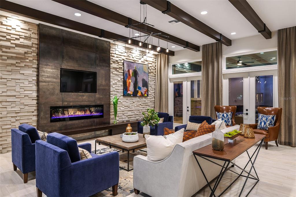 A living room features a stone accent wall, a fireplace, exposed ceiling beams, and blue furniture — 7545 LAUREATE BOULEVARD UNIT 7404, ORLANDO, FL