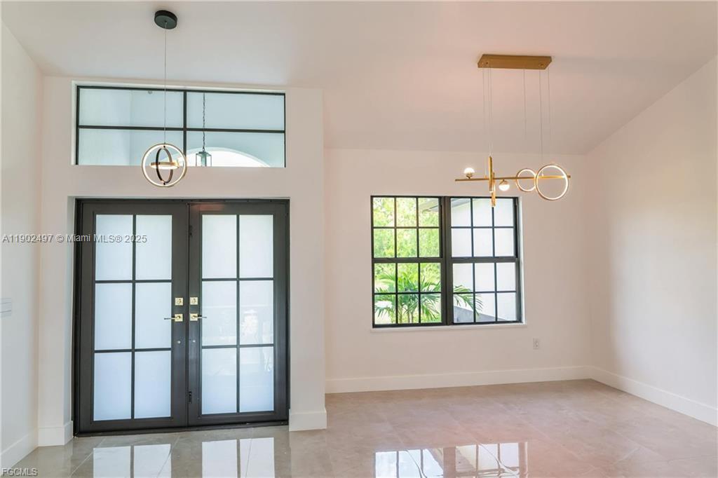 A bright entryway features double glass doors, a modern chandelier, and a large window — 1506 EIGHTH AVE, Lehigh Acres FL 33972, LEHIGH ACRES, FL