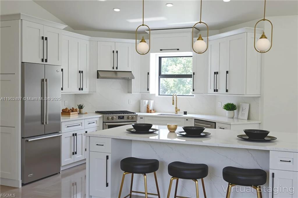 A modern kitchen features white cabinets, stainless steel appliances, a quartz island, and gold lighting — 1506 EIGHTH AVE, Lehigh Acres FL 33972, LEHIGH ACRES, FL