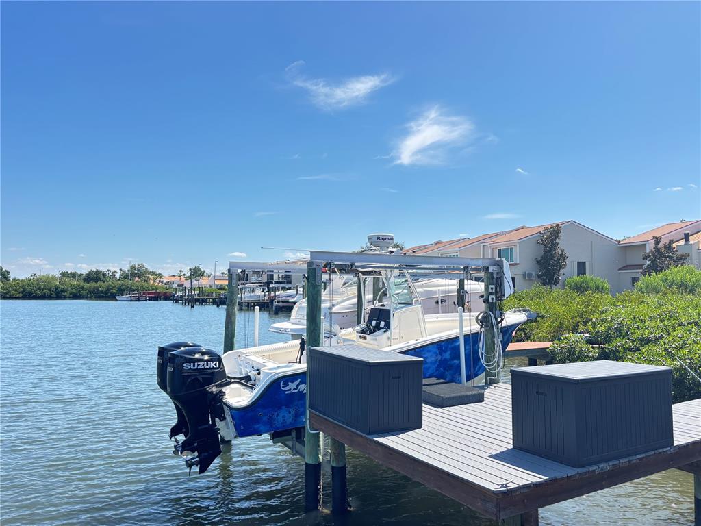A boat with dual Suzuki outboard motors is docked on a lift at a pier — 4364 OUTRIGGER LANE, TAMPA, FL