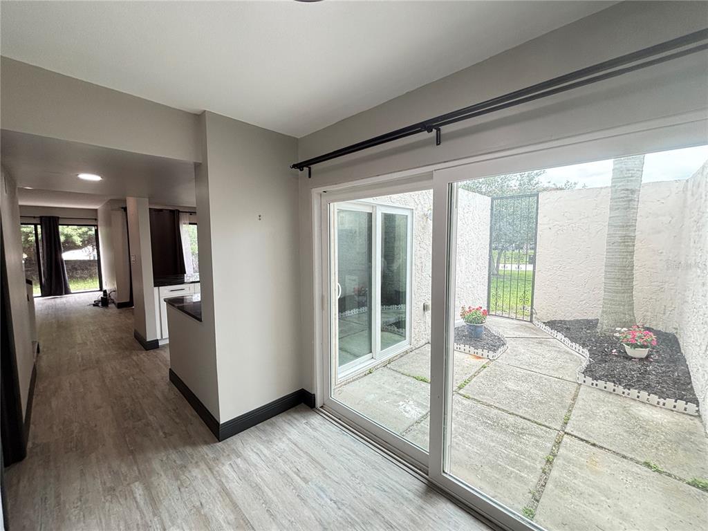 A room with light wood-look flooring features a sliding glass door opening to a patio — 4364 OUTRIGGER LANE, TAMPA, FL