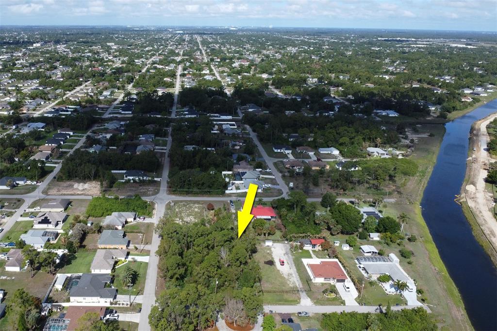 An aerial view shows a vacant, wooded residential lot marked by a yellow arrow — 1103 DOROTHY AVENUE N, LEHIGH ACRES, FL