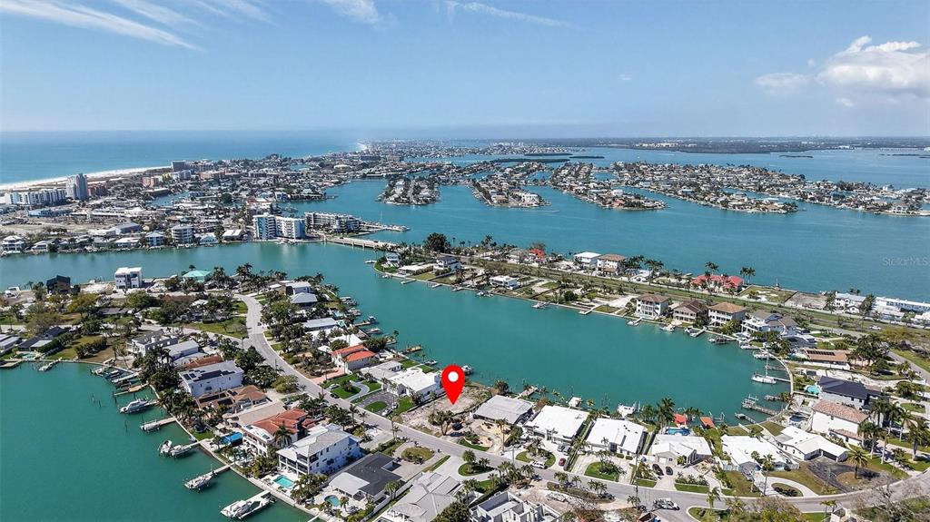 An aerial view shows a vacant waterfront lot marked with a red pin — 27 DOLPHIN DRIVE, TREASURE ISLAND, FL