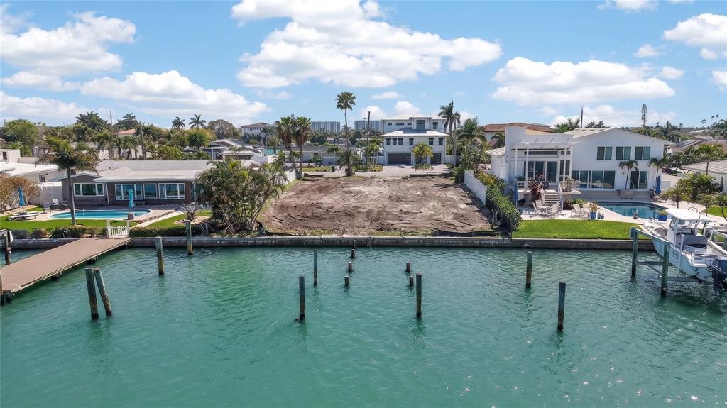 An aerial view shows a vacant waterfront lot situated between two houses with swimming pools — 27 DOLPHIN DRIVE, TREASURE ISLAND, FL
