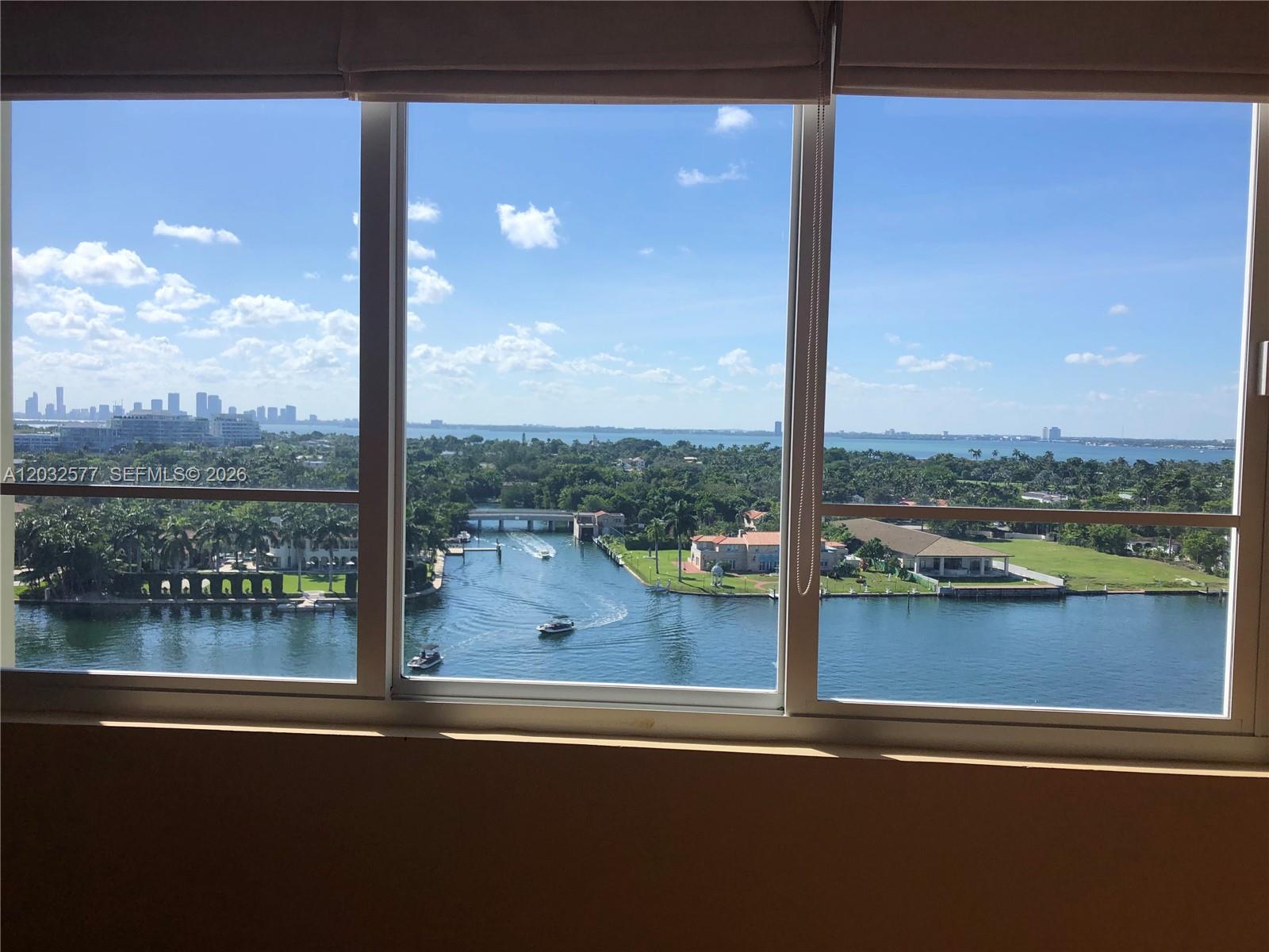 A view of a waterway, bridge, and distant city skyline through a large window — 5005 Collins Ave # 1202, Miami Beach FL 33140, MIAMI BEACH, FL