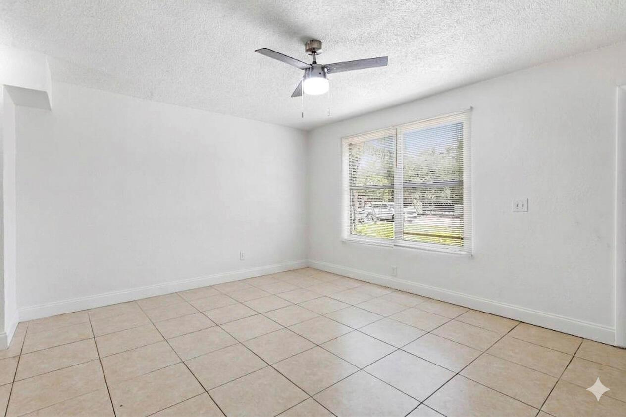 An empty room with white walls, beige tile flooring, and a ceiling fan — RIVIERA BEACH, FL
