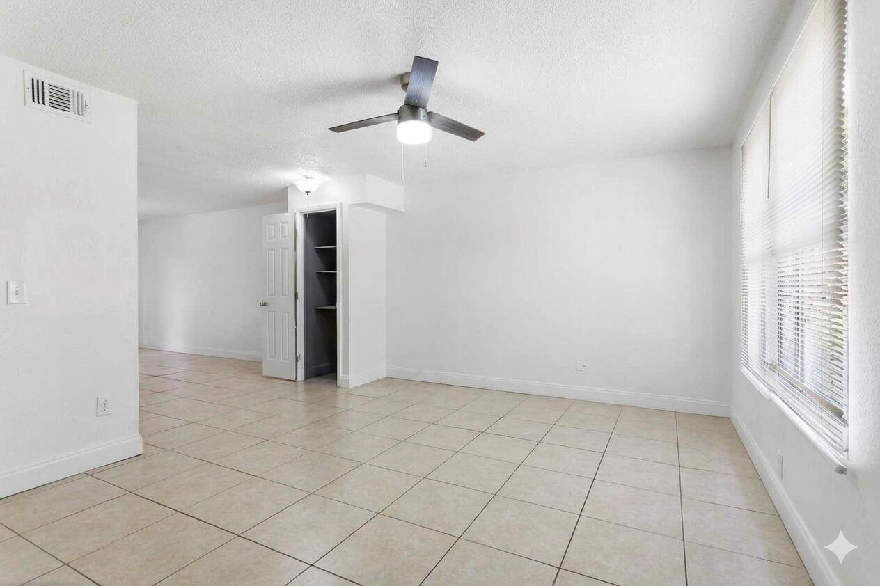 An empty room with white walls, tiled floors, a ceiling fan, and a built-in closet — RIVIERA BEACH, FL
