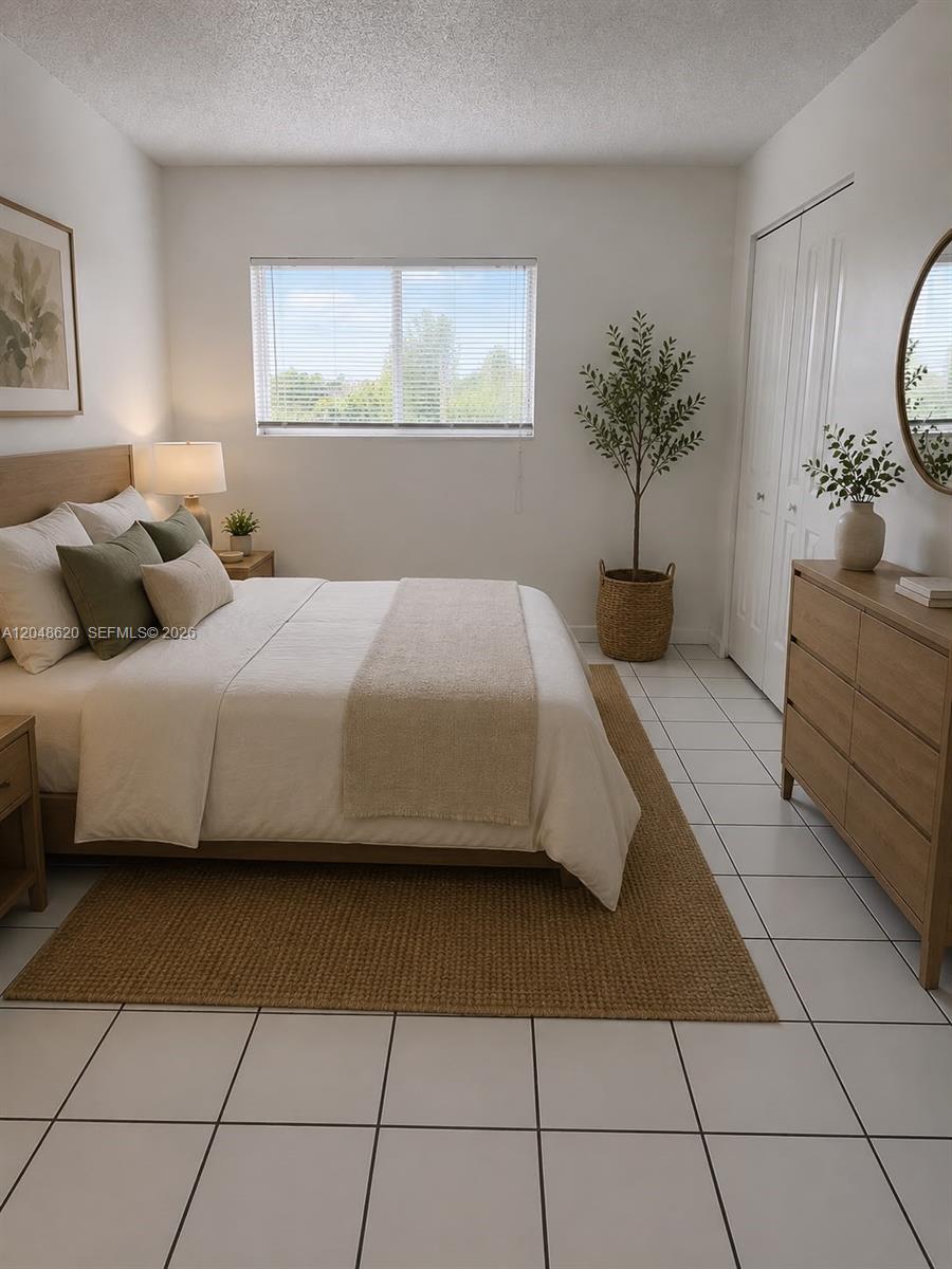 A bedroom features a bed with neutral bedding, a wooden dresser, and a potted plant — 600 NW 32nd Pl # 312, Miami FL 33125, MIAMI, FL