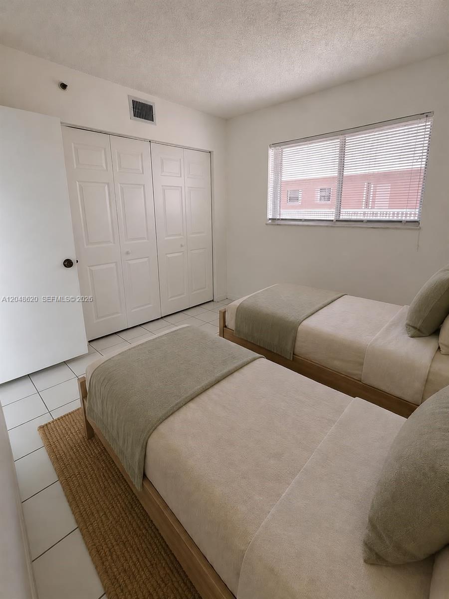 A bedroom features two twin beds, white tile flooring, and a white closet — 600 NW 32nd Pl # 312, Miami FL 33125, MIAMI, FL
