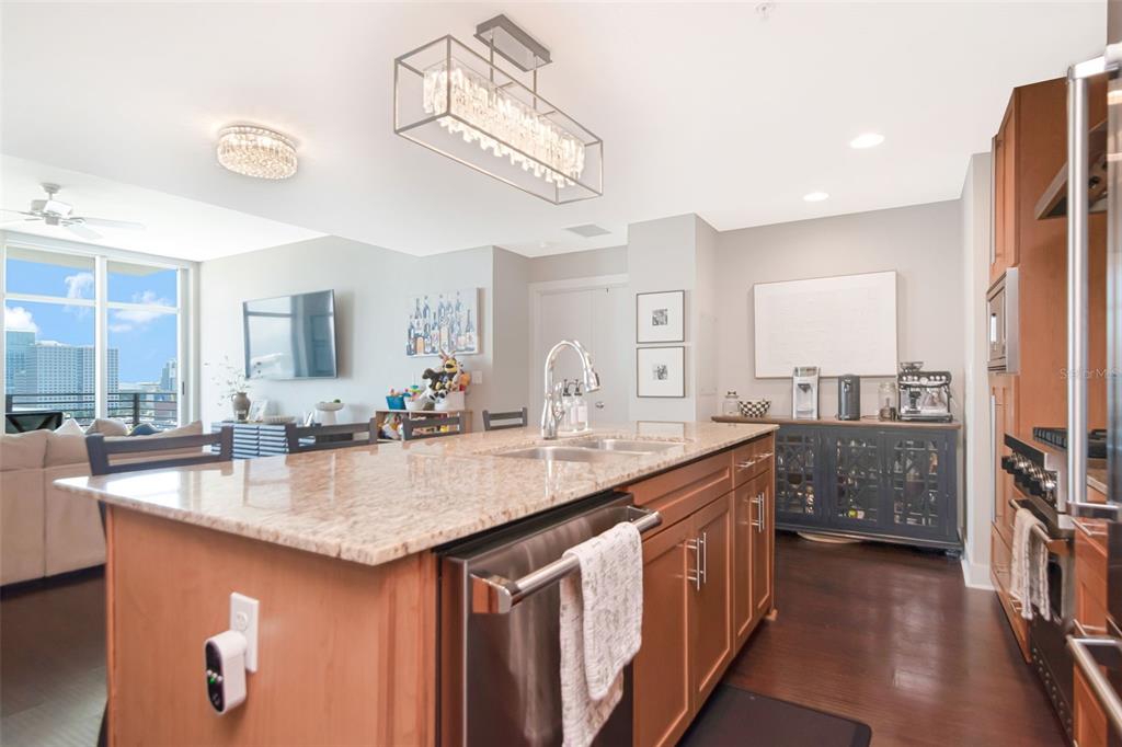 A kitchen features a granite-topped island, wooden cabinetry, and stainless steel appliances — 1120 E KENNEDY BOULEVARD UNIT 1211, TAMPA, FL