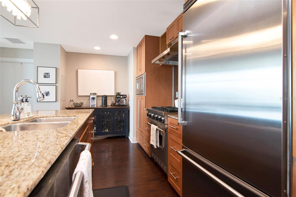 A modern kitchen features wood cabinets, stainless steel appliances, and a granite-topped island — 1120 E KENNEDY BOULEVARD UNIT 1211, TAMPA, FL