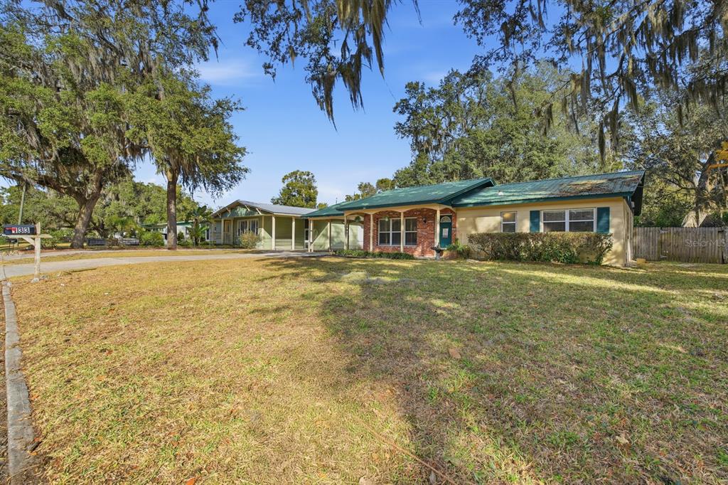 A single-story house with a green metal roof and brick accents sits on a lawn — 133 CRESTWOOD AVENUE, PALATKA, FL