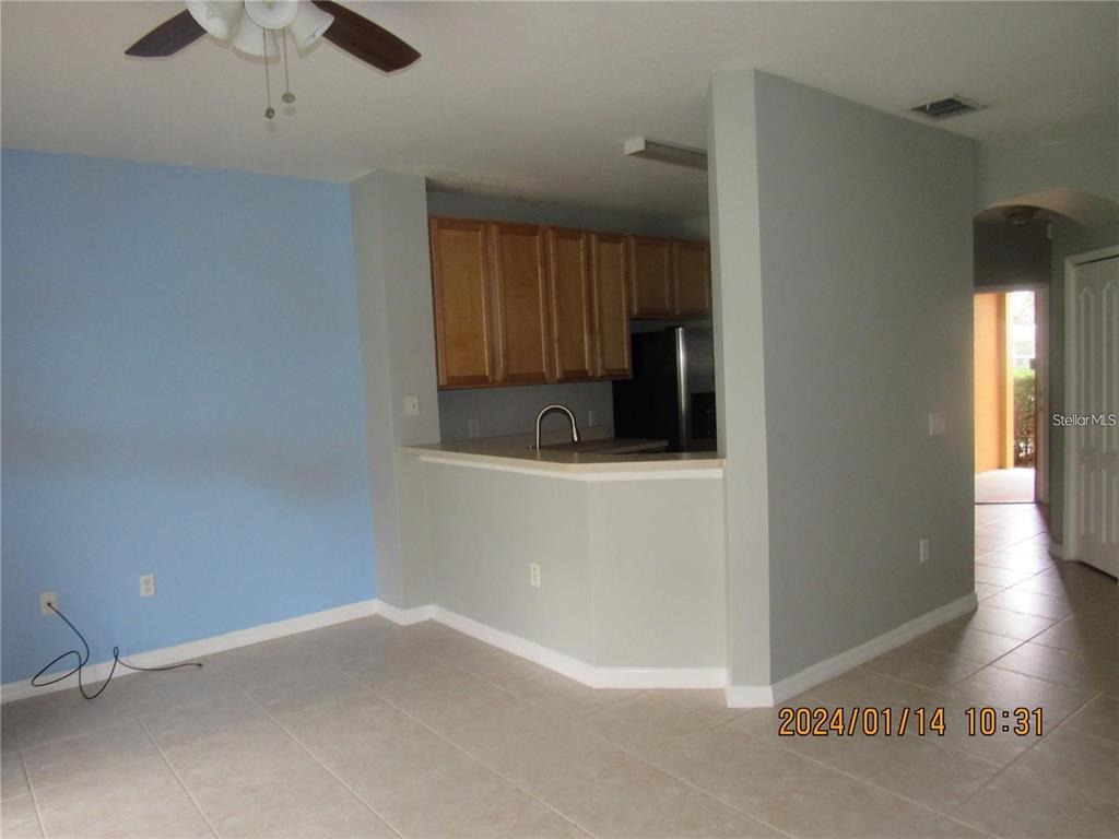 A kitchen with wooden cabinets and a breakfast bar overlooks a tiled living area — 244 CHELSEA DRIVE, DAVENPORT, FL