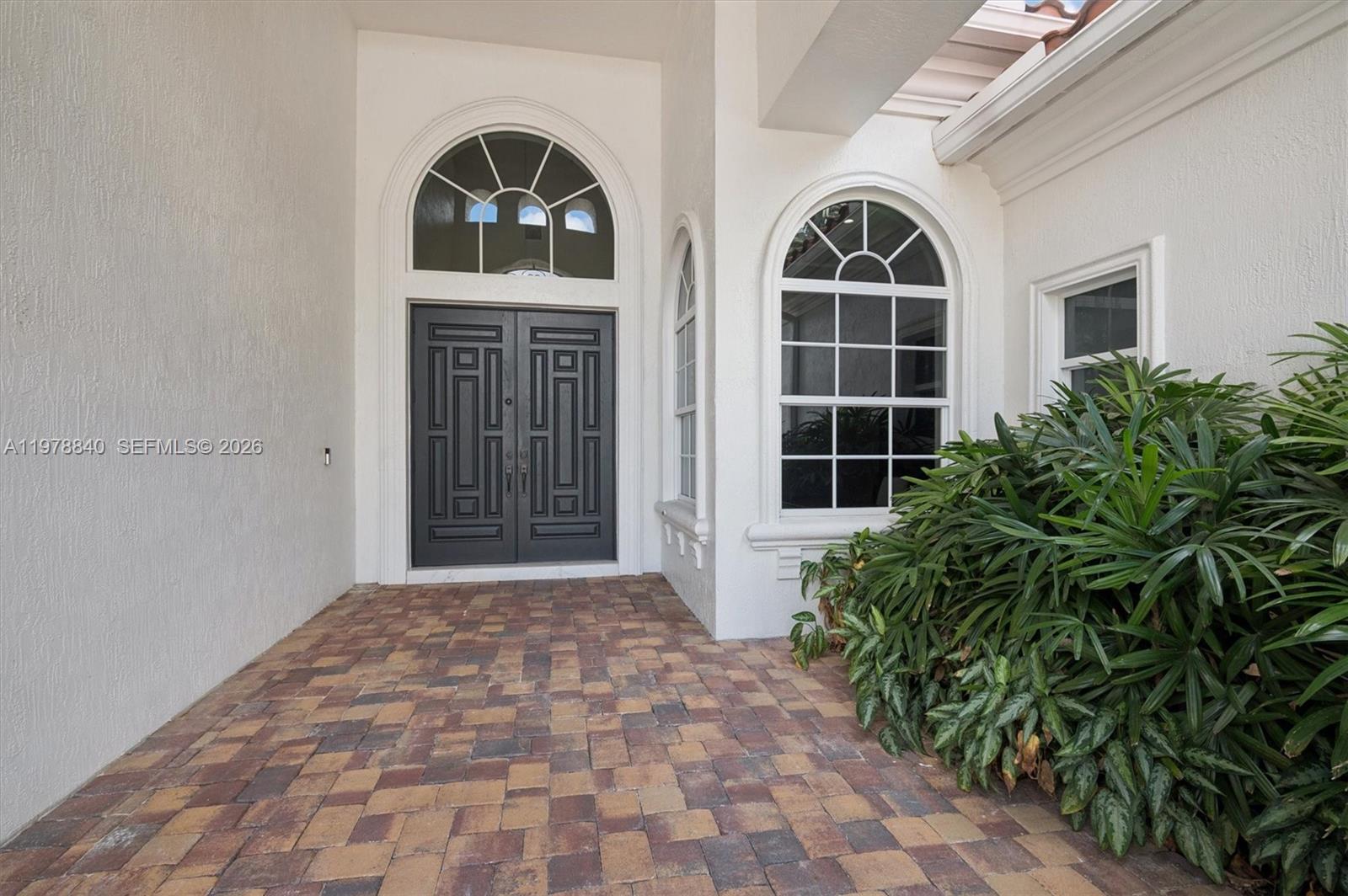 A paved entryway leads to a dark double door with an arched transom window — 12922 Grand Oaks Dr, Davie FL 33330, DAVIE, FL