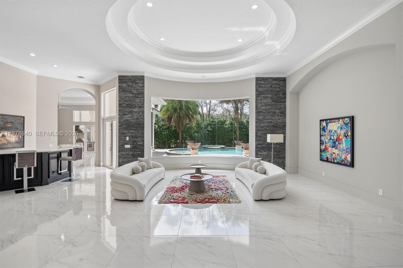 A spacious living room features white marble floors, two curved sofas, and a pool view — 12922 Grand Oaks Dr, Davie FL 33330, DAVIE, FL