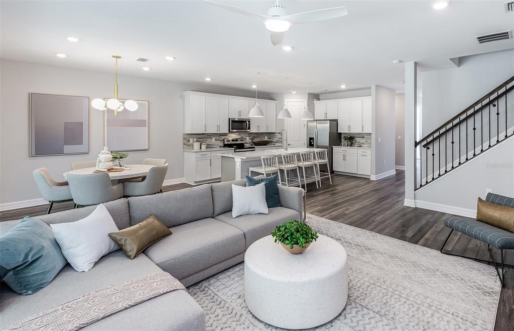 An open-concept living room and kitchen featuring gray flooring, white cabinetry, and a sectional sofa — 7465 SUMMER COURT, SARASOTA, FL