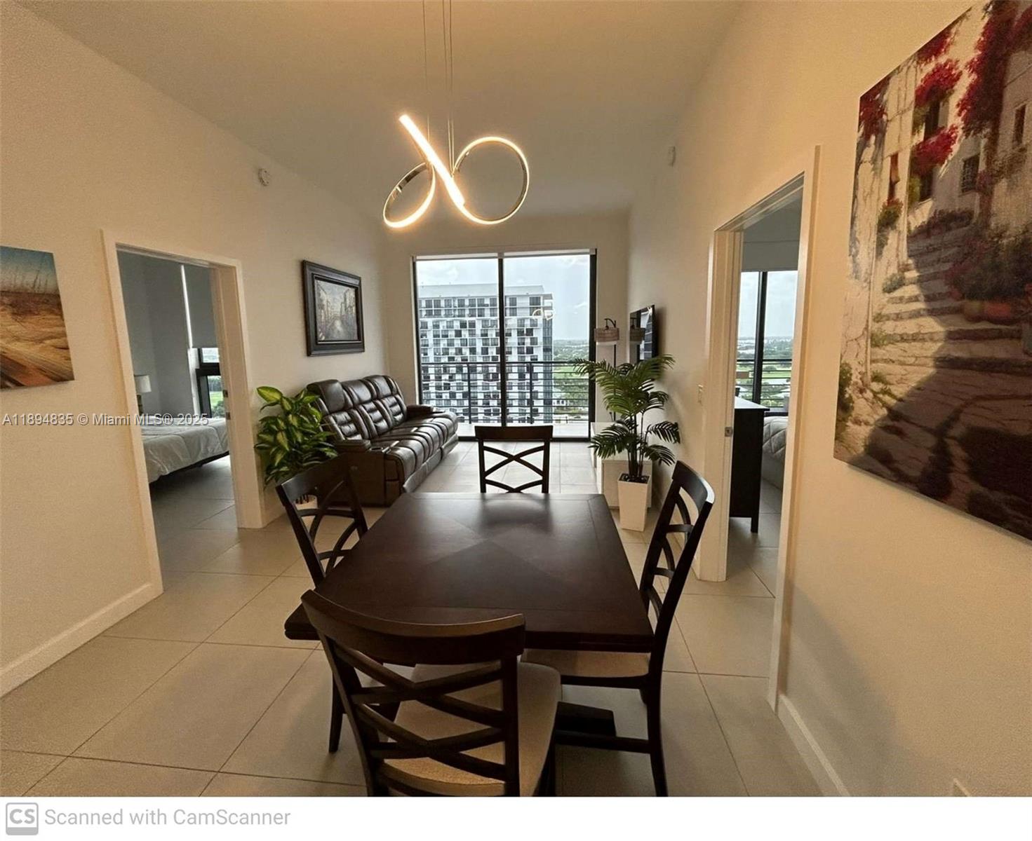 A dining area with a dark wood table and chairs sits before a living room — 5350 NW 84th Ave # 1818, Doral FL 33166, DORAL, FL
