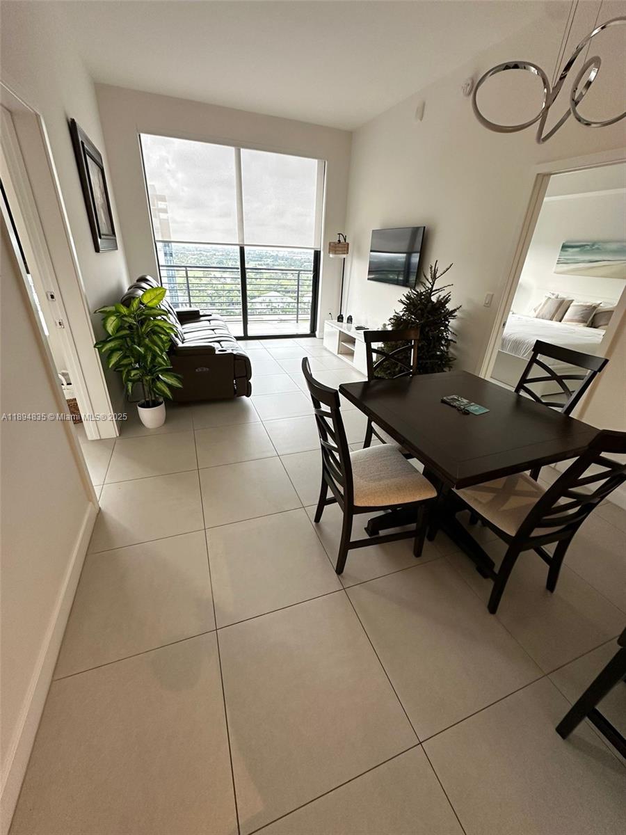 A dining area and living room with tile floors lead to a balcony with city views — 5350 NW 84th Ave # 1818, Doral FL 33166, DORAL, FL