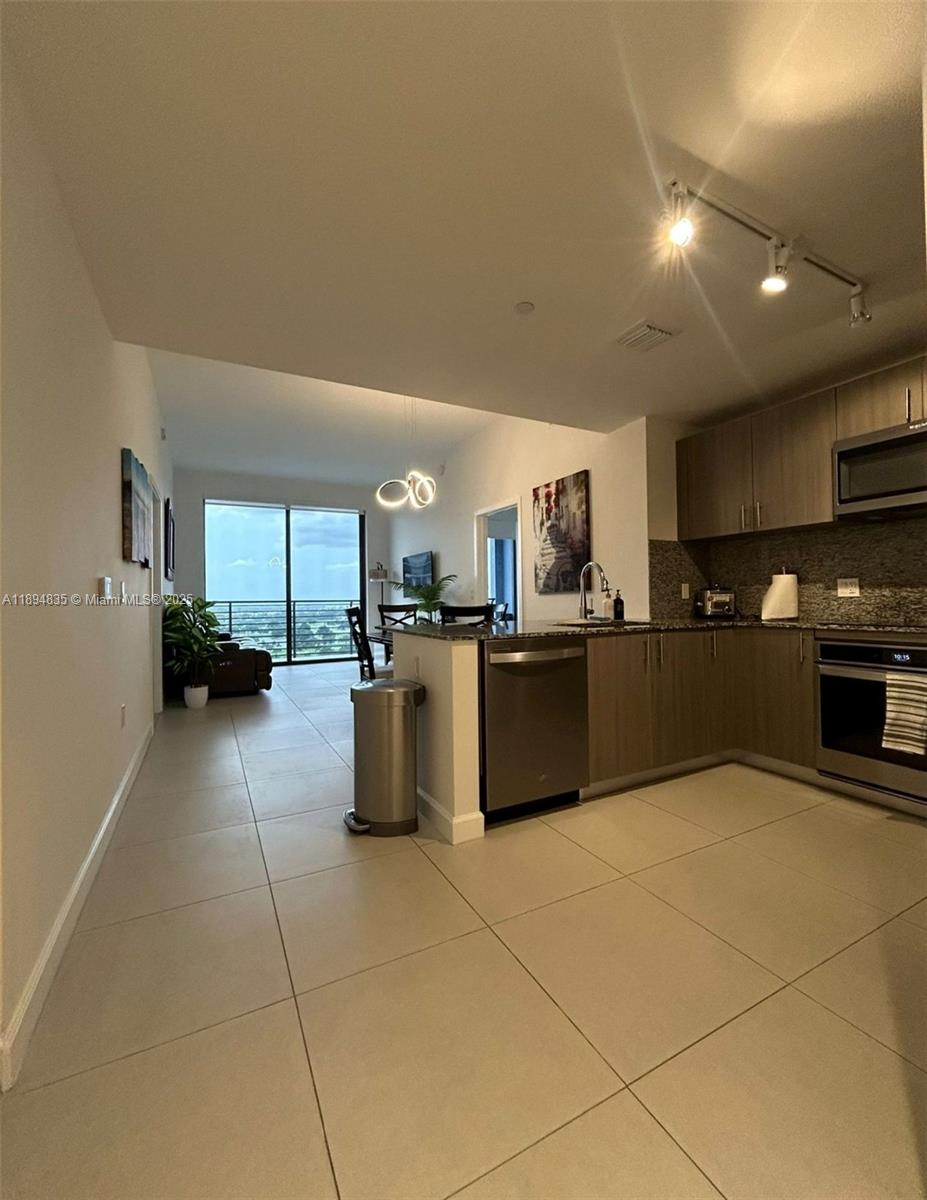 A modern kitchen with stainless steel appliances opens into a living area with balcony access — 5350 NW 84th Ave # 1818, Doral FL 33166, DORAL, FL