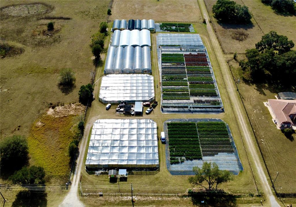 An aerial view shows a plant nursery with several greenhouses and outdoor growing beds — 23010 WOLF BRANCH ROAD, SORRENTO, FL