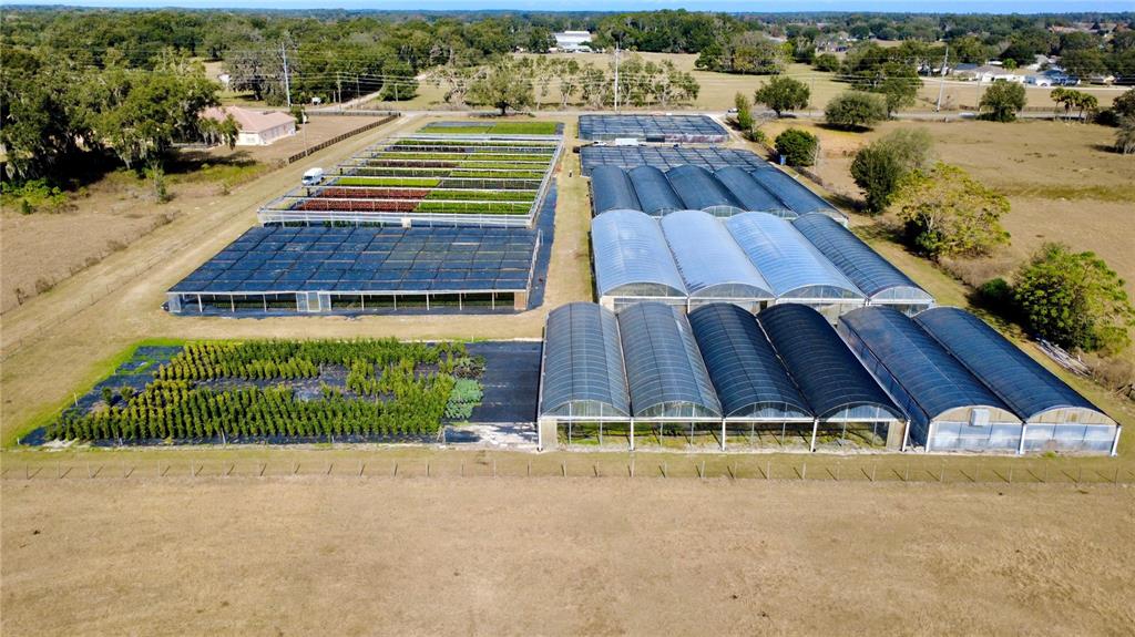 An aerial view shows a plant nursery with multiple greenhouses and outdoor growing areas — 23010 WOLF BRANCH ROAD, SORRENTO, FL