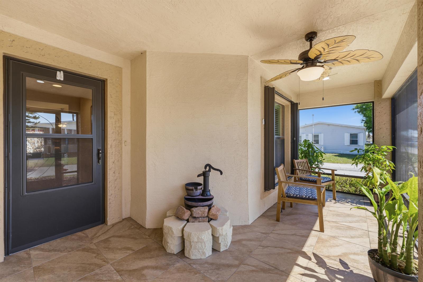 A covered patio features tile flooring, a ceiling fan, two wooden chairs, and a water feature — 6700 Dulce Real Avenue, Fort Pierce FL 34951, FORT PIERCE, FL