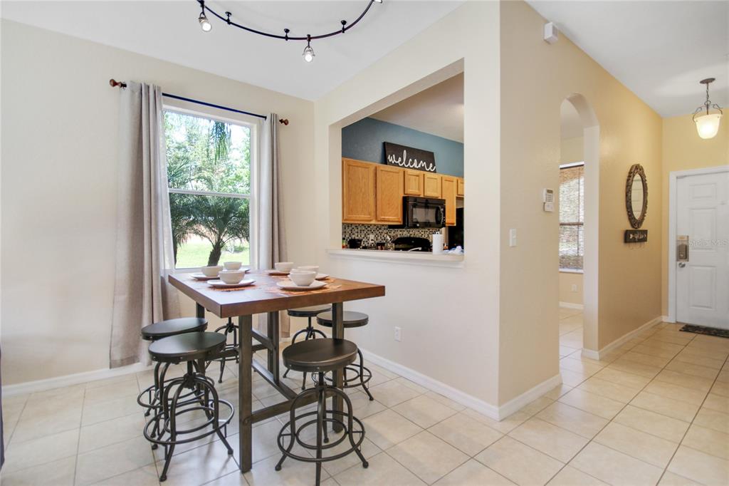 A dining area features a wooden table with stools, tile flooring, and a kitchen pass-through — 2740 COUPE STREET, KISSIMMEE, FL