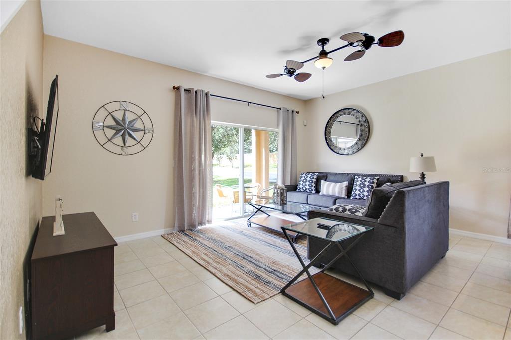 A living room features tile floors, a gray sectional sofa, and sliding glass patio doors — 2740 COUPE STREET, KISSIMMEE, FL