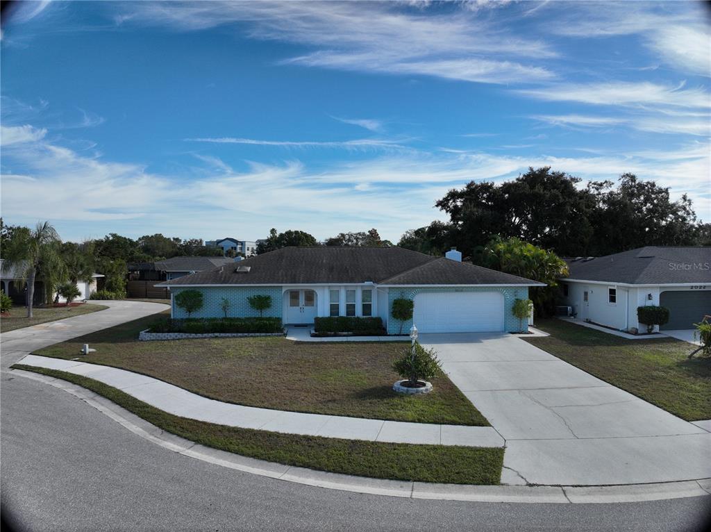 A single-story house with a light blue brick exterior, a two-car garage, and a driveway — 2042 COUNTRY MEADOWS PLACE, SARASOTA, FL