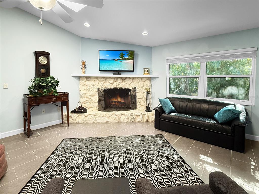 A living room features a stone fireplace, a black leather sofa, and a patterned rug — 2042 COUNTRY MEADOWS PLACE, SARASOTA, FL