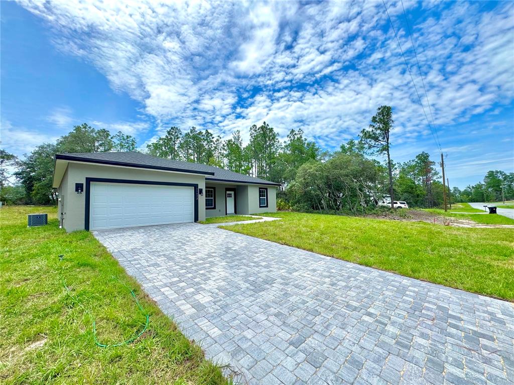 A single-story house with a paved driveway, white garage door, and surrounding trees — 11789 N PROVIDENCE WAY, CITRUS SPRINGS, FL