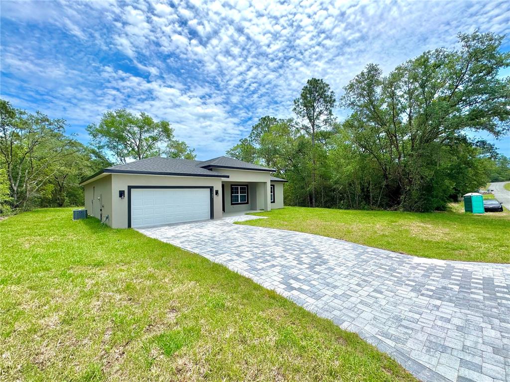A single-story house with a paved driveway, white garage door, and surrounding green lawn — 11789 N PROVIDENCE WAY, CITRUS SPRINGS, FL