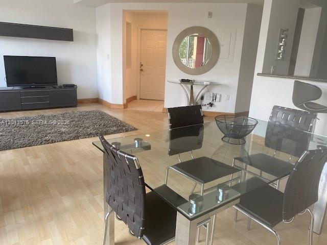 A dining area with a glass table and chairs sits adjacent to a living room — 11001 NW 83rd St # 204, Doral FL 33178, DORAL, FL
