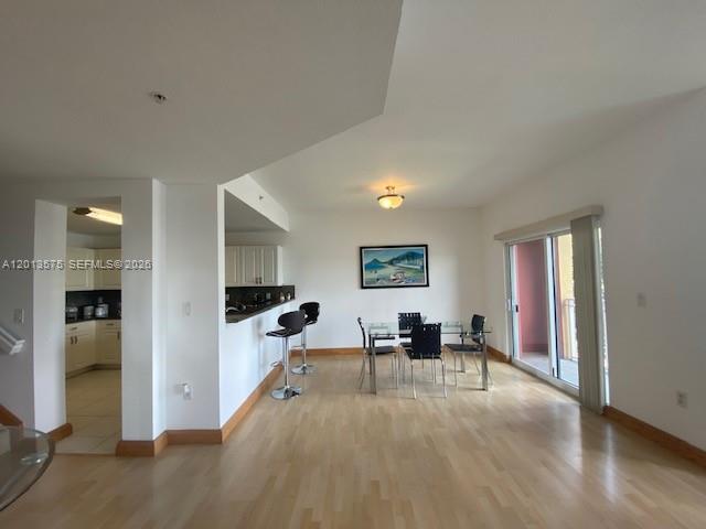 An open-concept dining area features light wood flooring, a breakfast bar, and sliding glass doors — 11001 NW 83rd St # 204, Doral FL 33178, DORAL, FL
