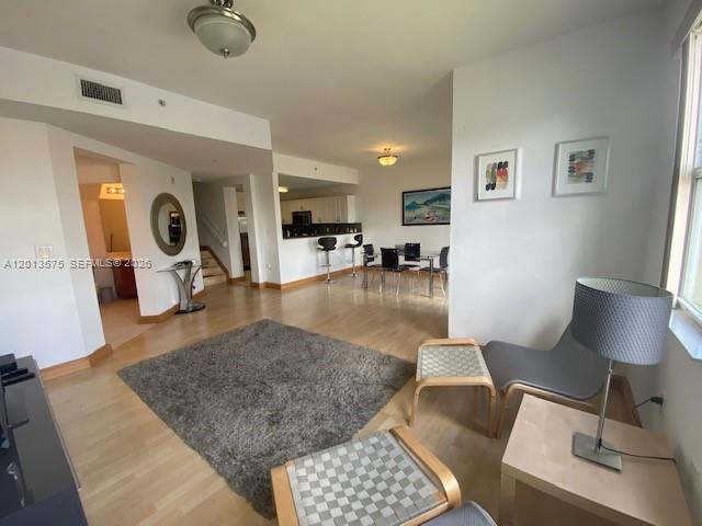 An open-concept living and dining area features light wood flooring and a gray area rug — 11001 NW 83rd St # 204, Doral FL 33178, DORAL, FL