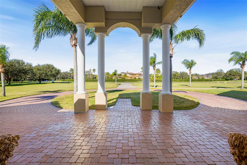 A paved driveway leads to a covered entryway featuring four white columns and palm trees — 11518 HAMMOCK OAKS COURT, LITHIA, FL