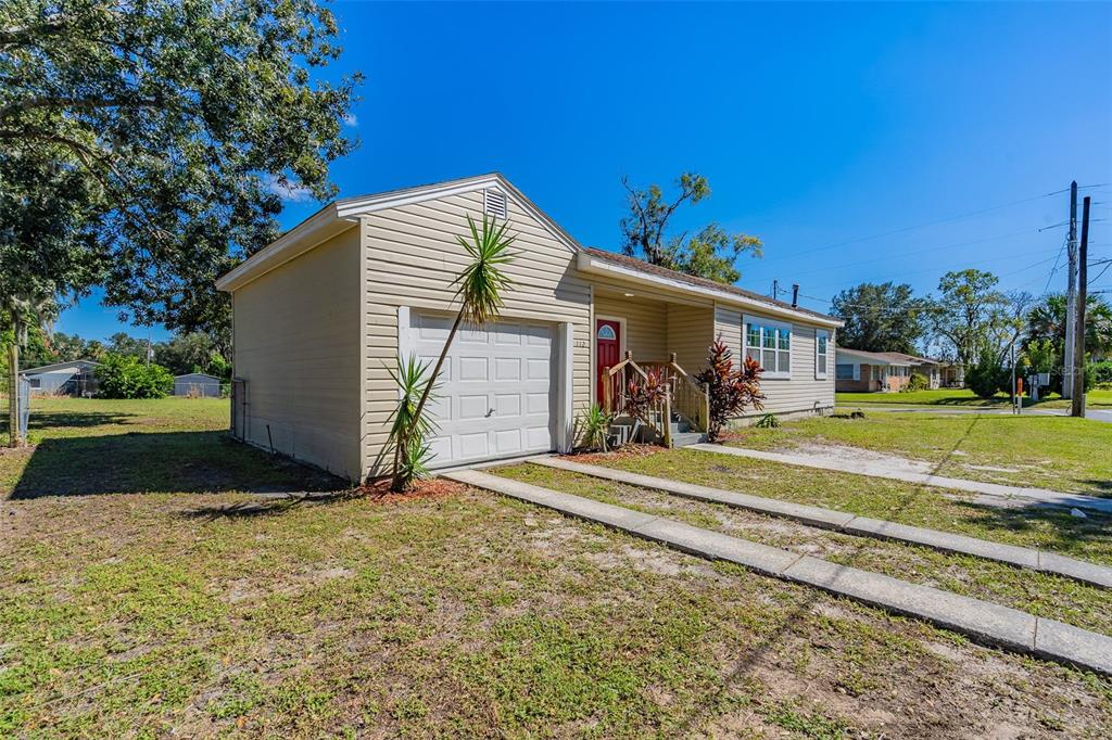 A single-story house with beige siding, a front-facing garage, and a small porch — 112 S MOSS STREET, LEESBURG, FL