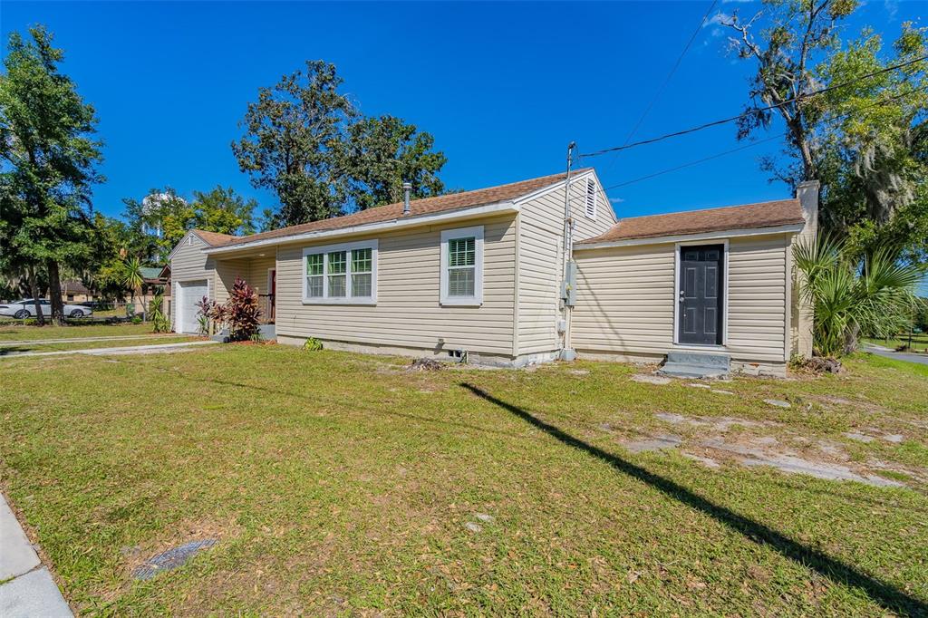 A single-story house with light-colored siding, a brown shingled roof, and a black front door — 112 S MOSS STREET, LEESBURG, FL